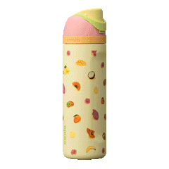 Owala Birthday Bash 24oz FreeSip Just Ripe; soft pale yellow body covered with colorful tropical fruit illustrations — mangoes, pineapples, and papayas — with a coral-pink flip cap